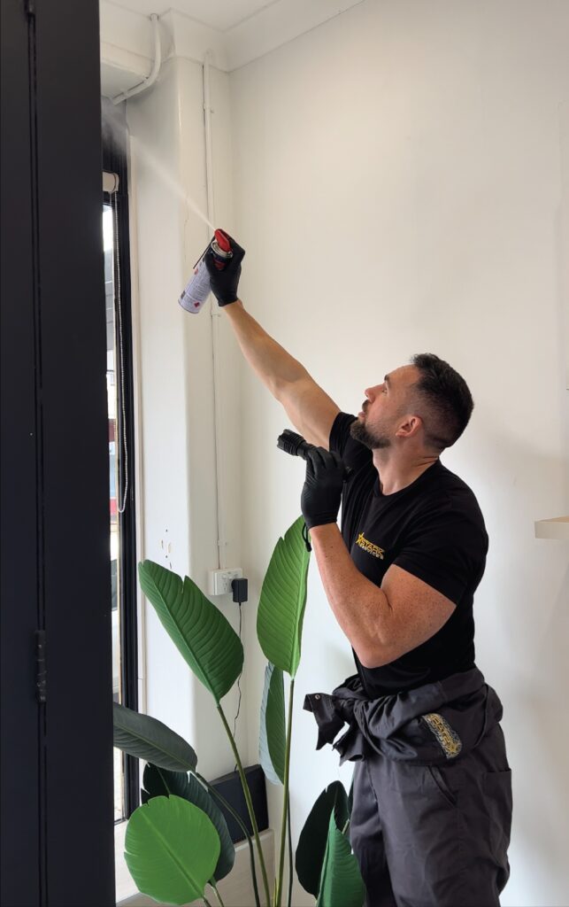 Stark Pest Solutions technician treating skirting and wall voids in a Sydney office for pest control